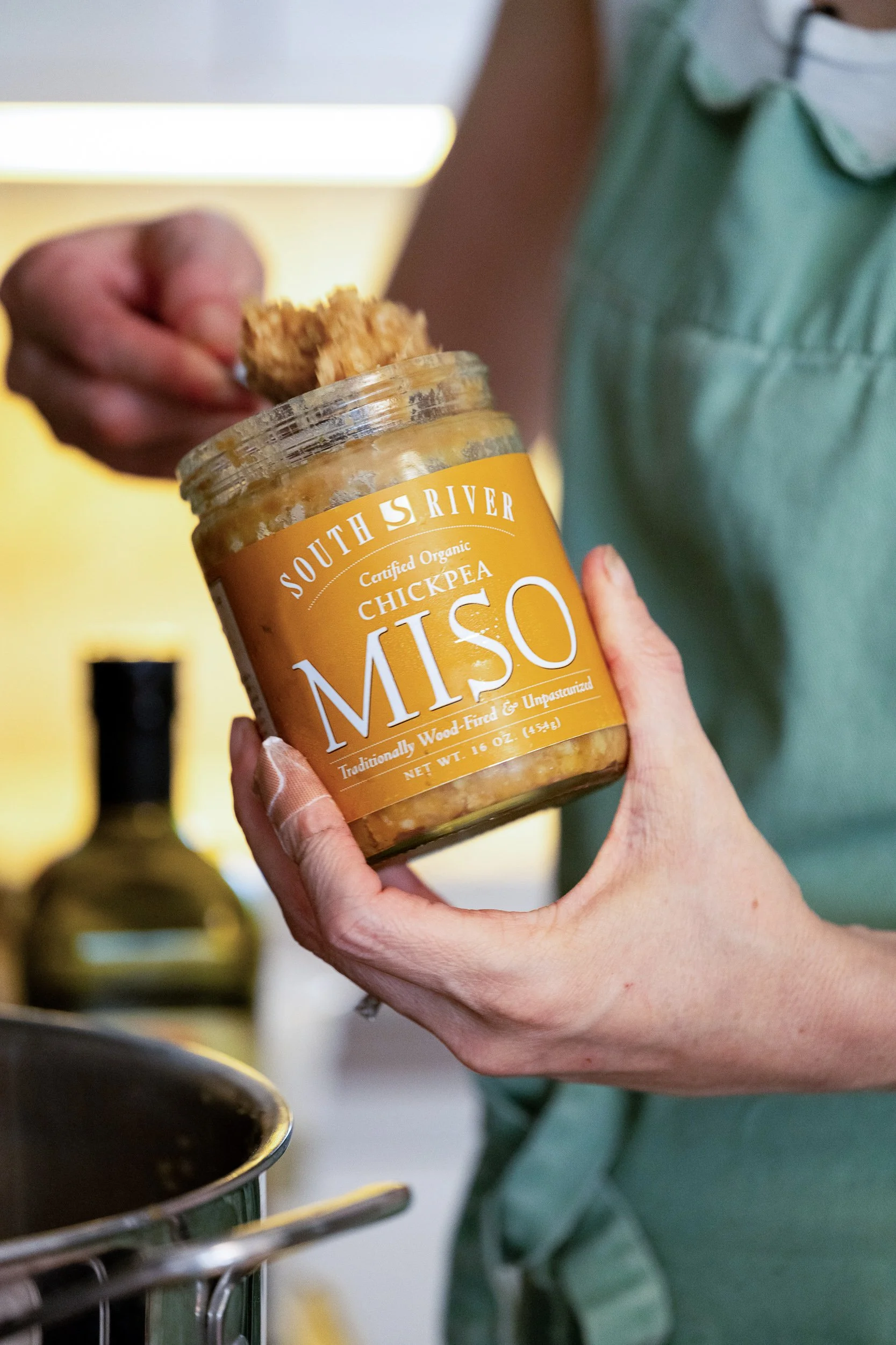 Hands holding South River Miso jar in kitchen, food brand and ingredient photography

