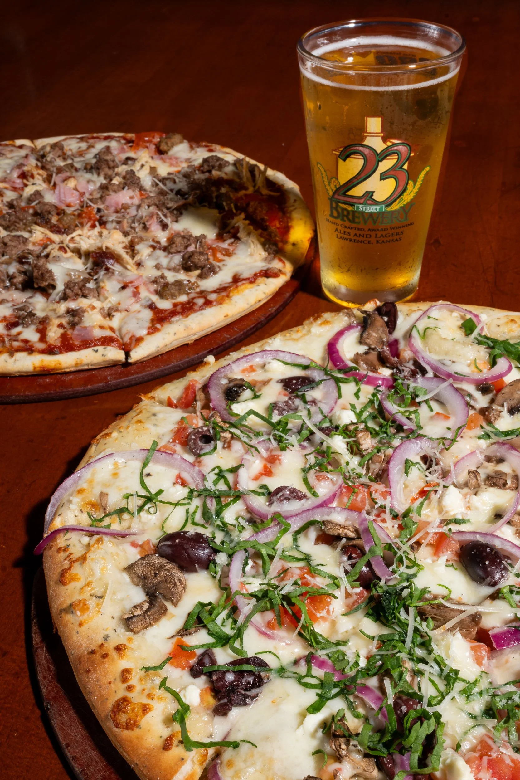 Two pizzas with 23rd Street Brewery branded pint glass, Kansas City brewery food photography
