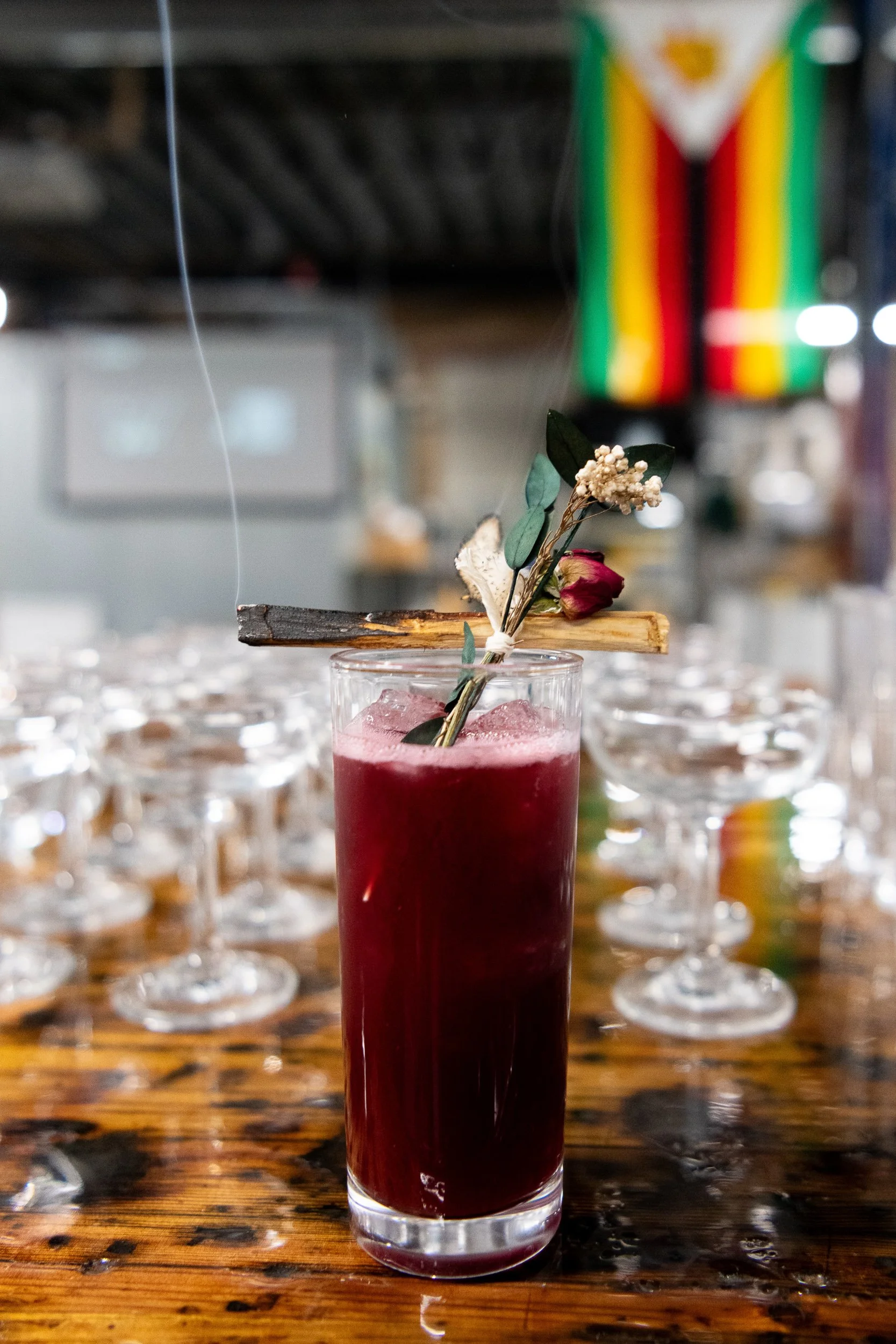 Crimson cocktail with herb garnish and long straw, craft cocktail bar photography Kansas City