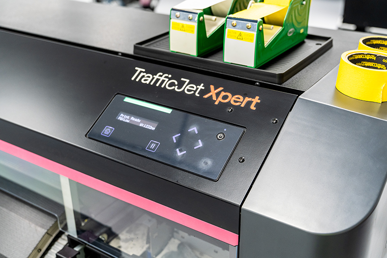 TrafficJet Xpert printing machine with yellow and green tape dispensers on top and yellow wristbands next to it.