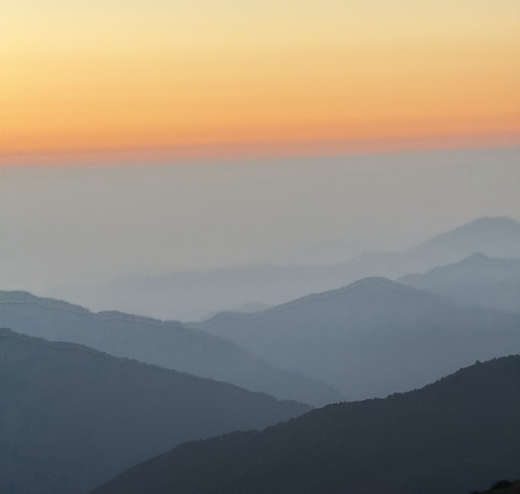 Sunset over a mountain range with layered silhouettes and a colorful sky.
