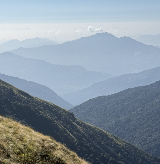 Scenic view of multiple mountain ridges with misty blue layers and a partly cloudy sky.