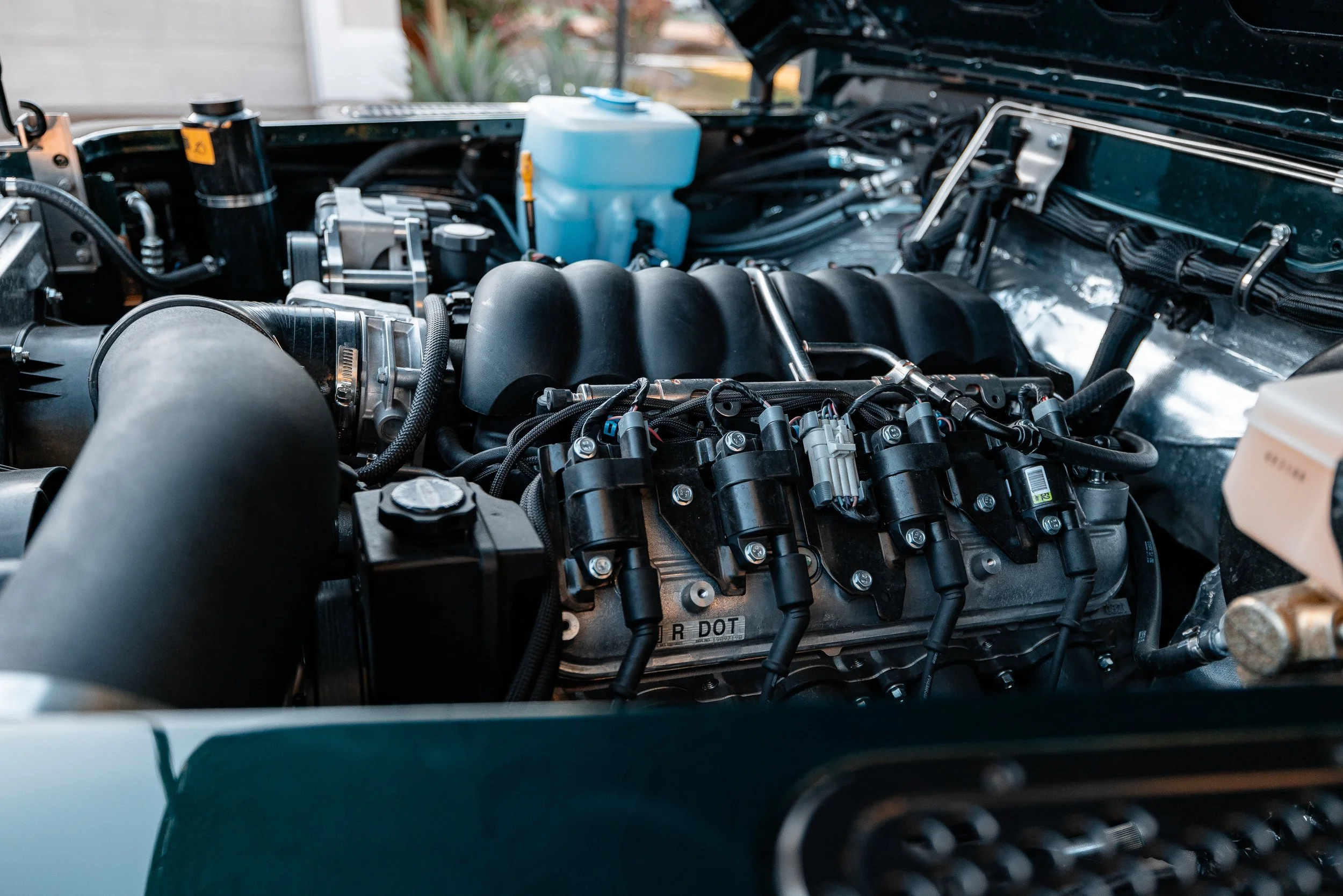Close-up view of a car engine with various components, hoses, and wires visible beneath the open hood.