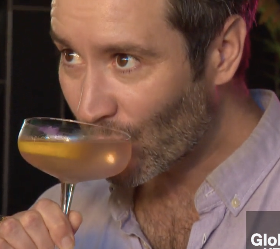 Andrew Paul sips a cocktail from a coupe glass garnished with a lemon wedge.