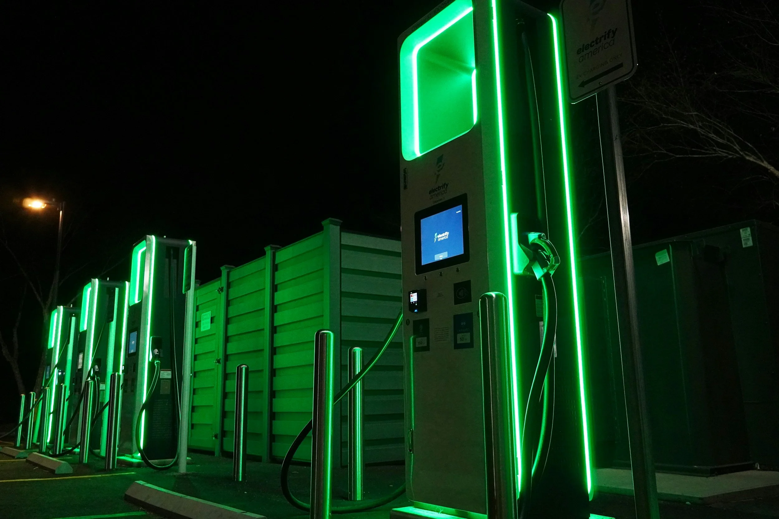 Electric vehicle charging stations at night with green LED lights.