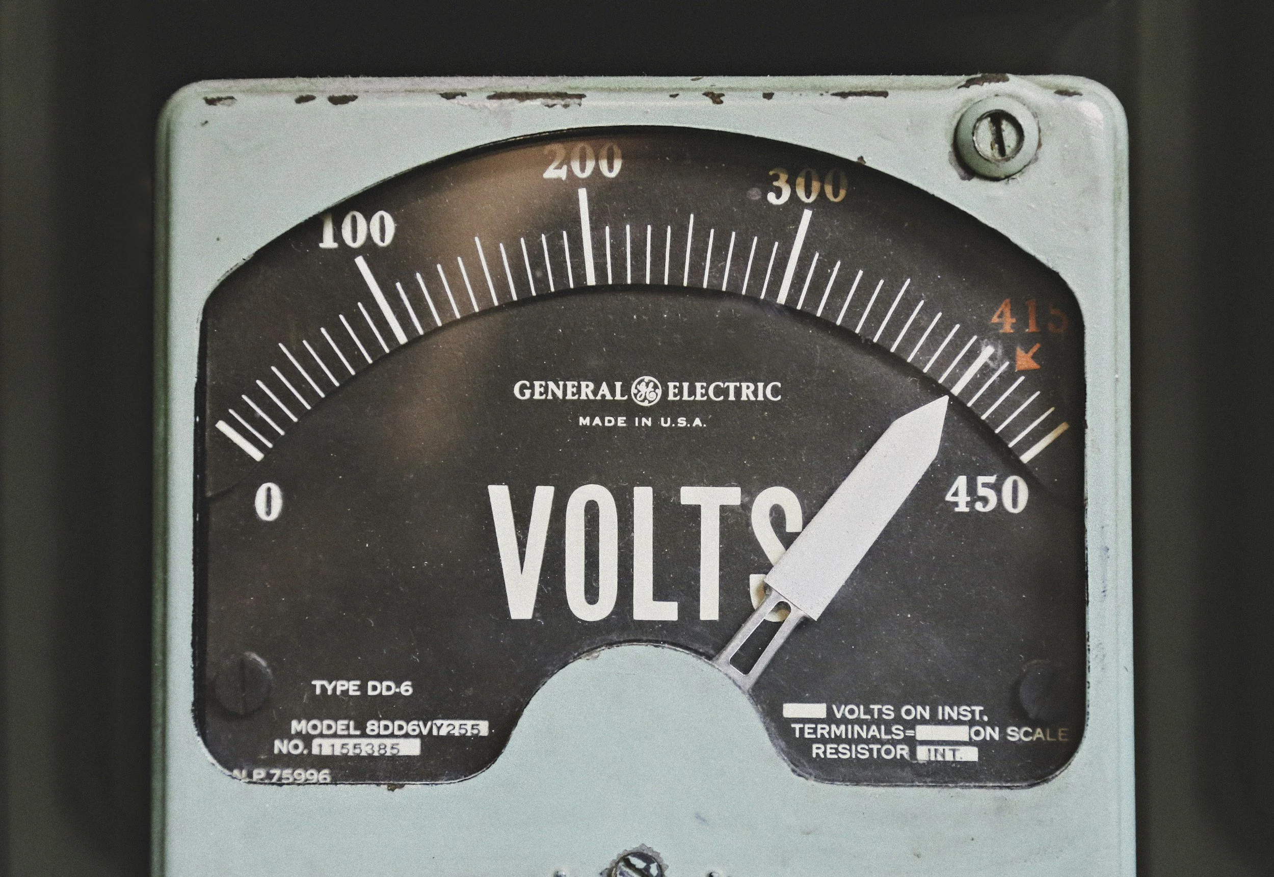 A vintage analog voltmeter gauge by General Electric, showing voltage levels, with a needle pointing to just over 400 volts.