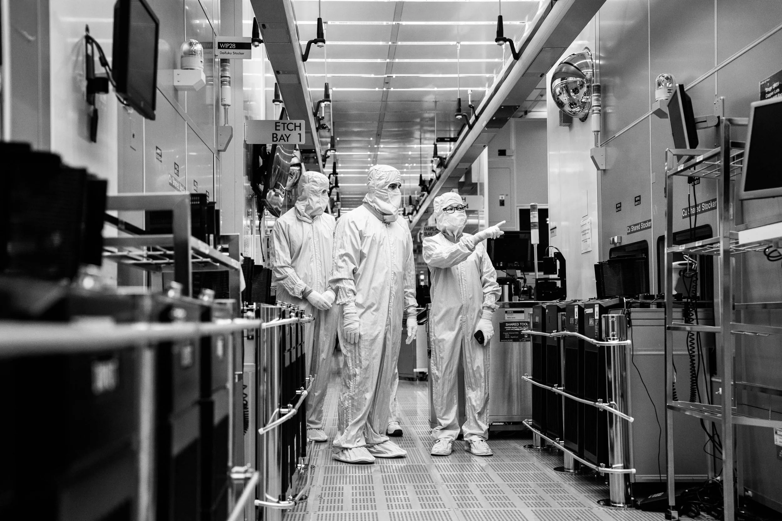 Scientists in cleanroom suits working in a high-tech laboratory with electronic equipment.
