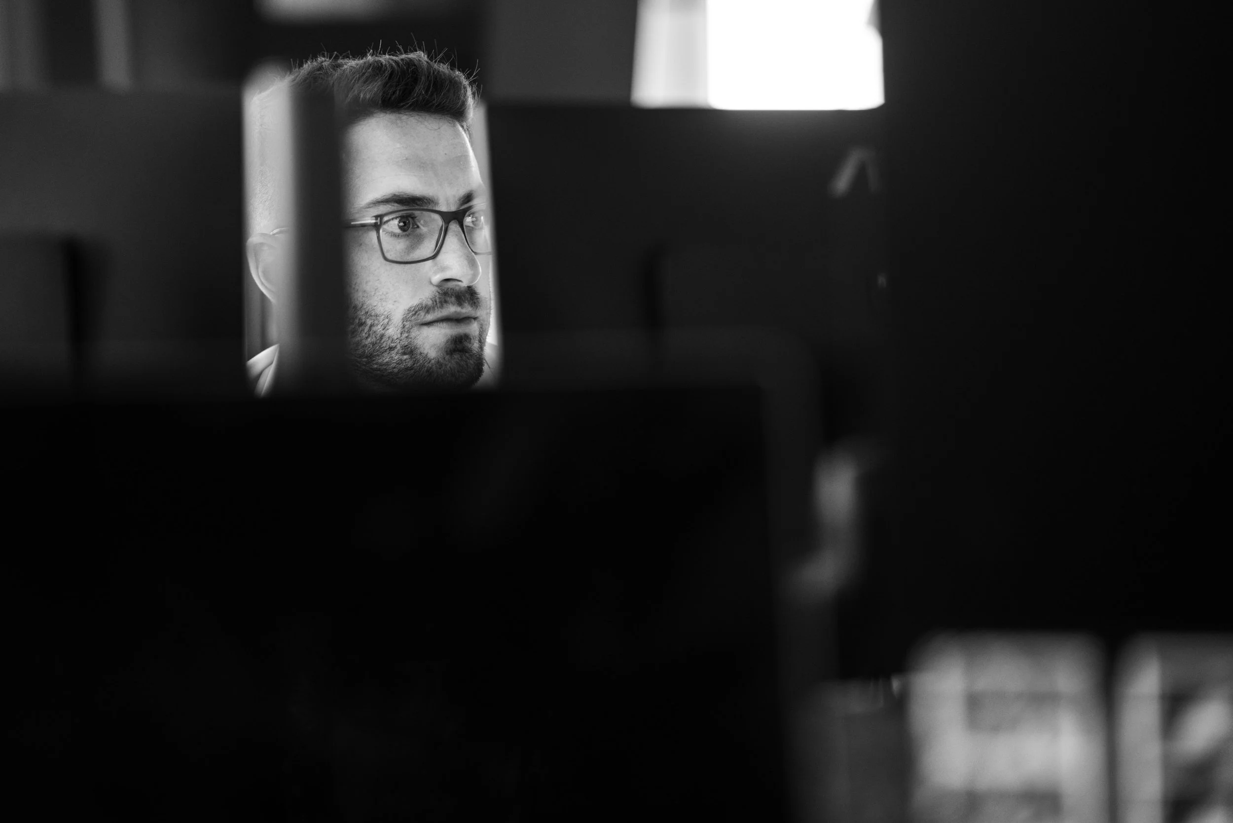 Black and white photo of a man with glasses looking at a computer screen