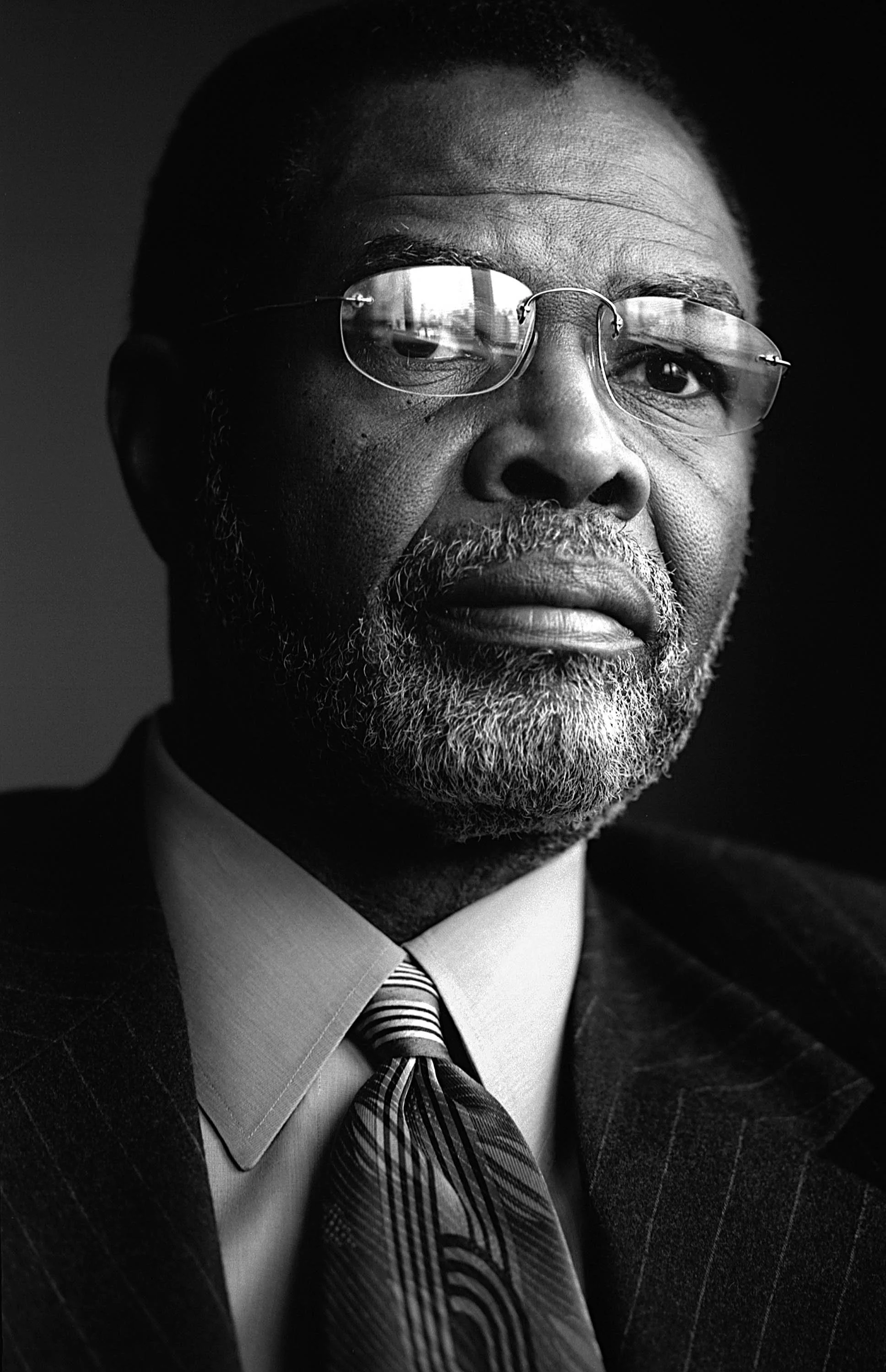 Black and white portrait of a middle-aged man with glasses, beard, and mustache, wearing a suit, shirt, and tie.