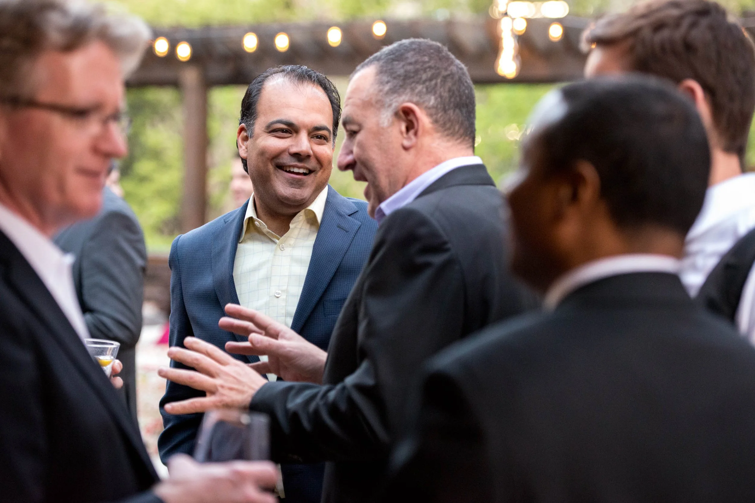 People in suits engaging in conversation at an outdoor event.