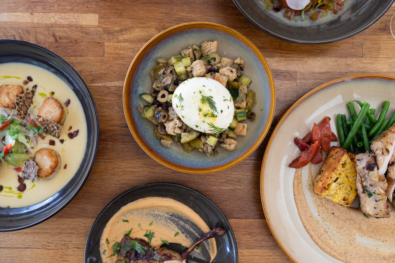A spread of seasonal summer dishes on a table top by The Stables at Belmont