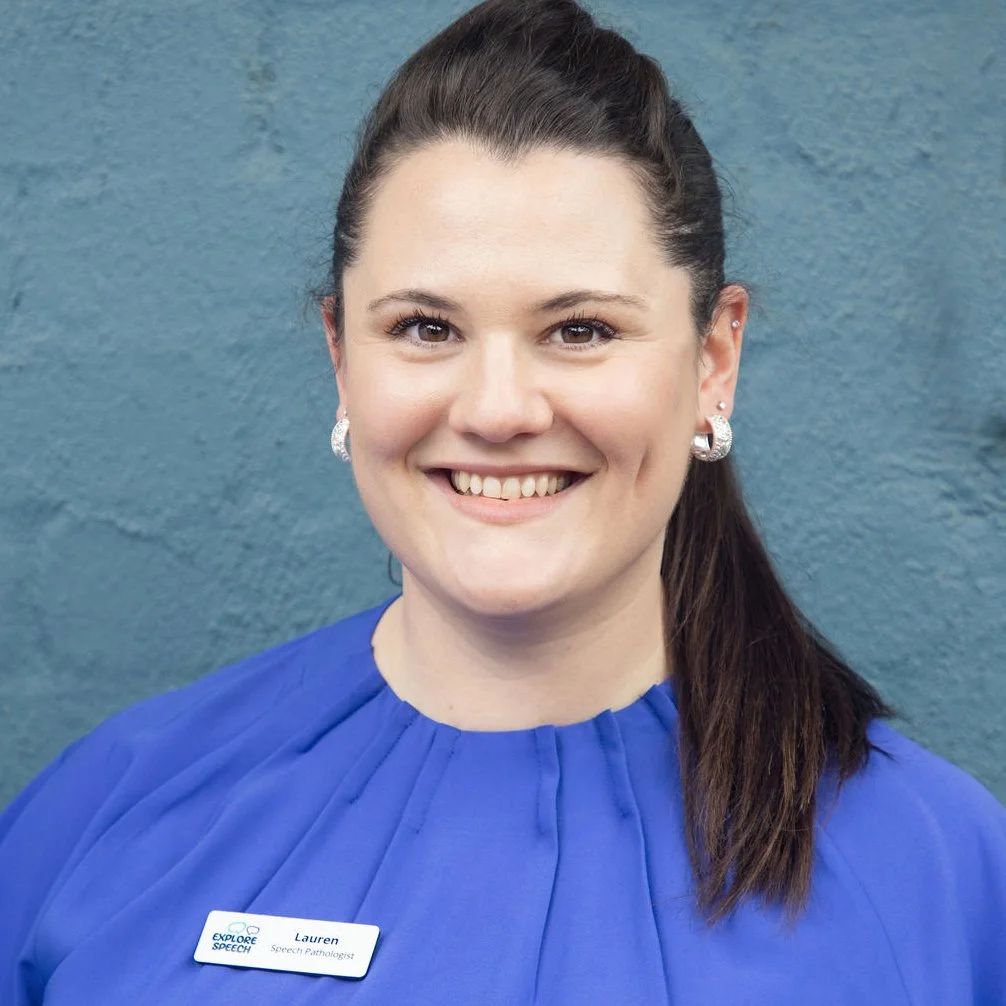 A woman smiling, wearing a blue blouse and a name tag that reads 'Lauren Speech Pathologist', with a blue background.