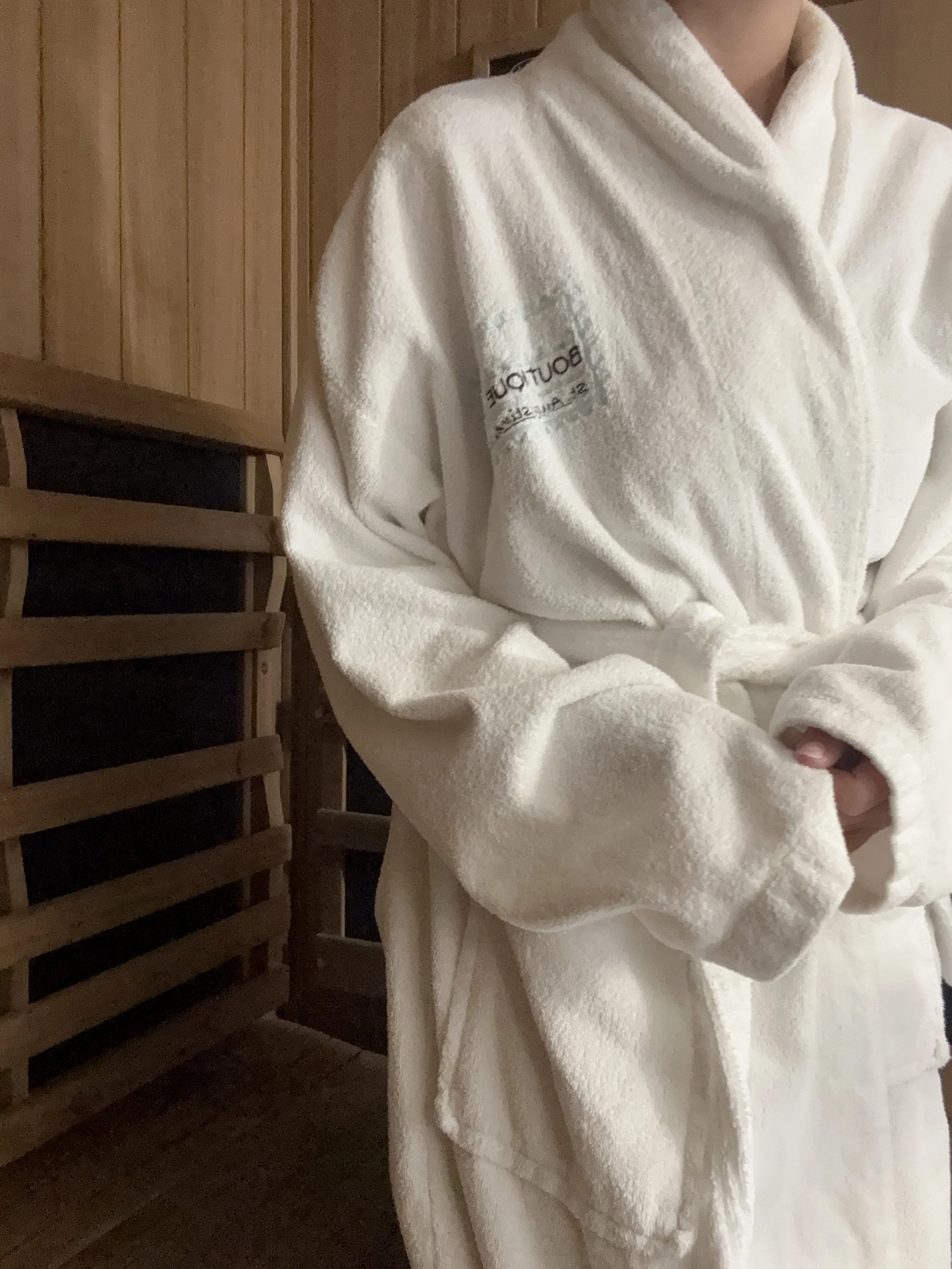 Person wearing a white bathrobe in a room with wood-paneled walls and wooden furniture.