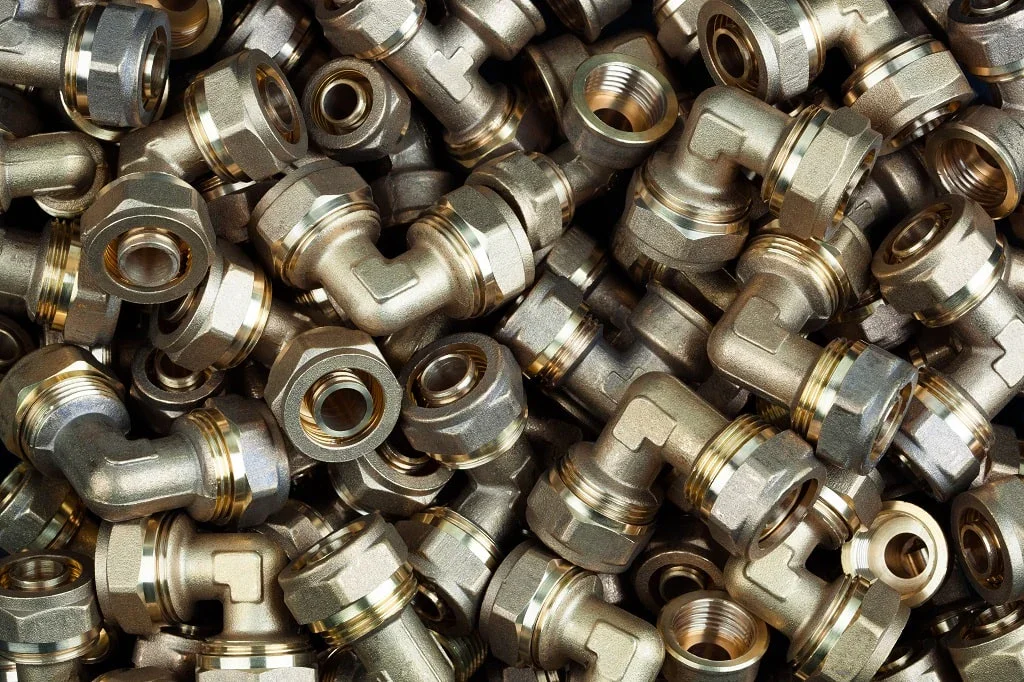 A large pile of metal pipe fittings, including elbows and threaded connectors, in various angles.