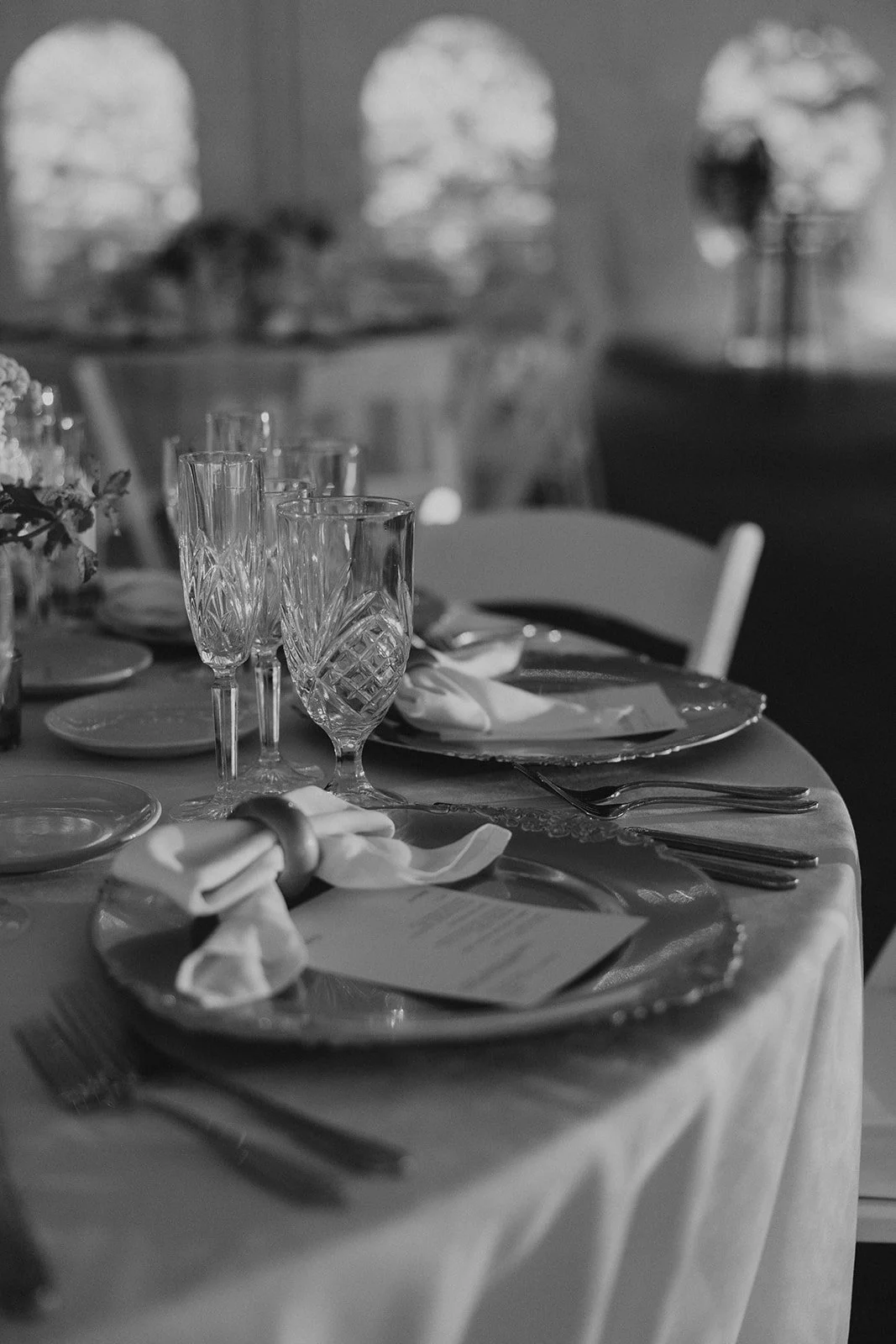 A formal dining table set with glassware, plates, napkins, and silverware in a decorated room.