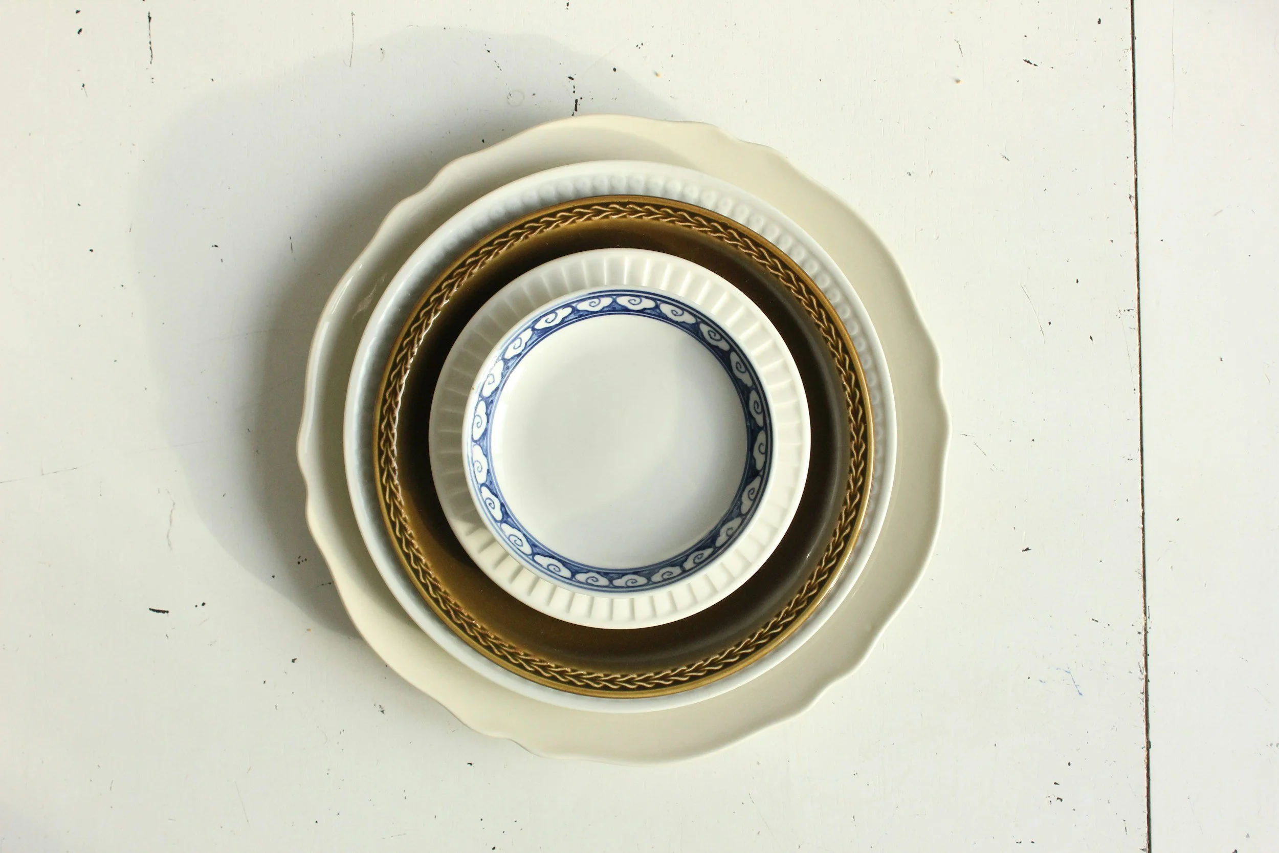 A stack of four nested bowls with different colors and designs, arranged on a white surface against a plain background. handmade bowls. wedding china