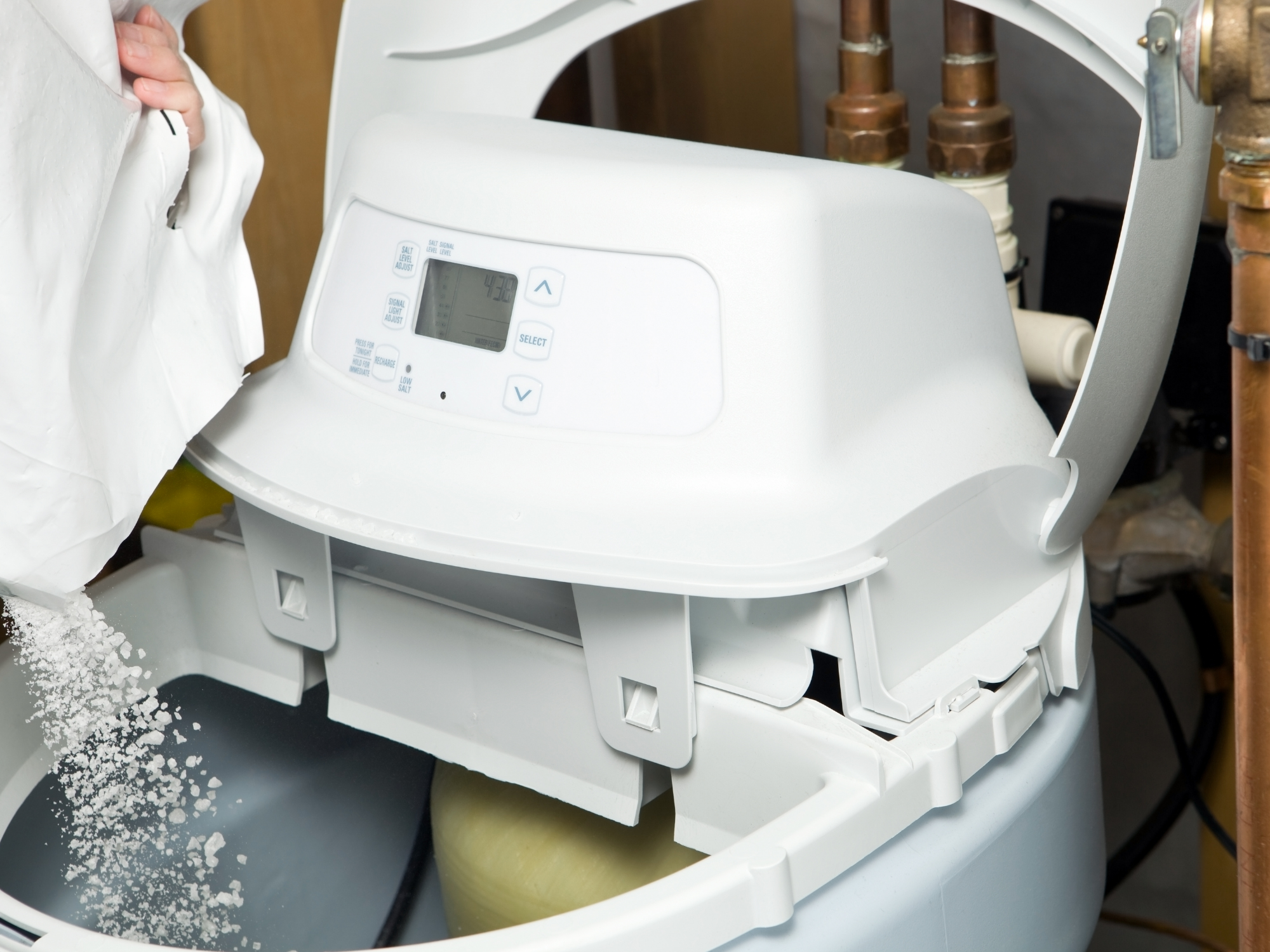 A water softener machine with digital display, pipes, and a salt reservoir, used for water treatment in a home or commercial setting.