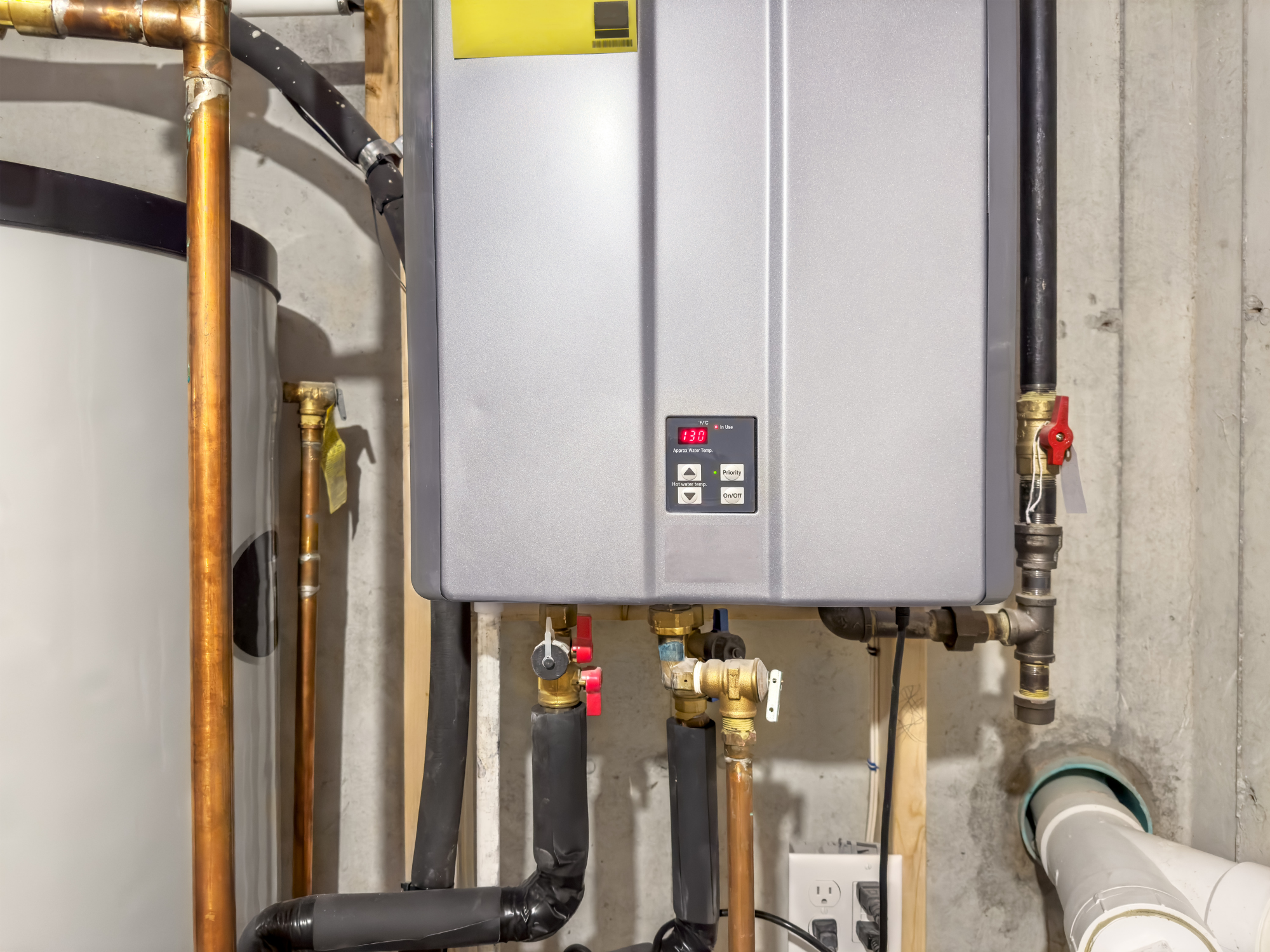 A water heater system with various pipes, valves, and a digital display showing 130 degrees Fahrenheit.