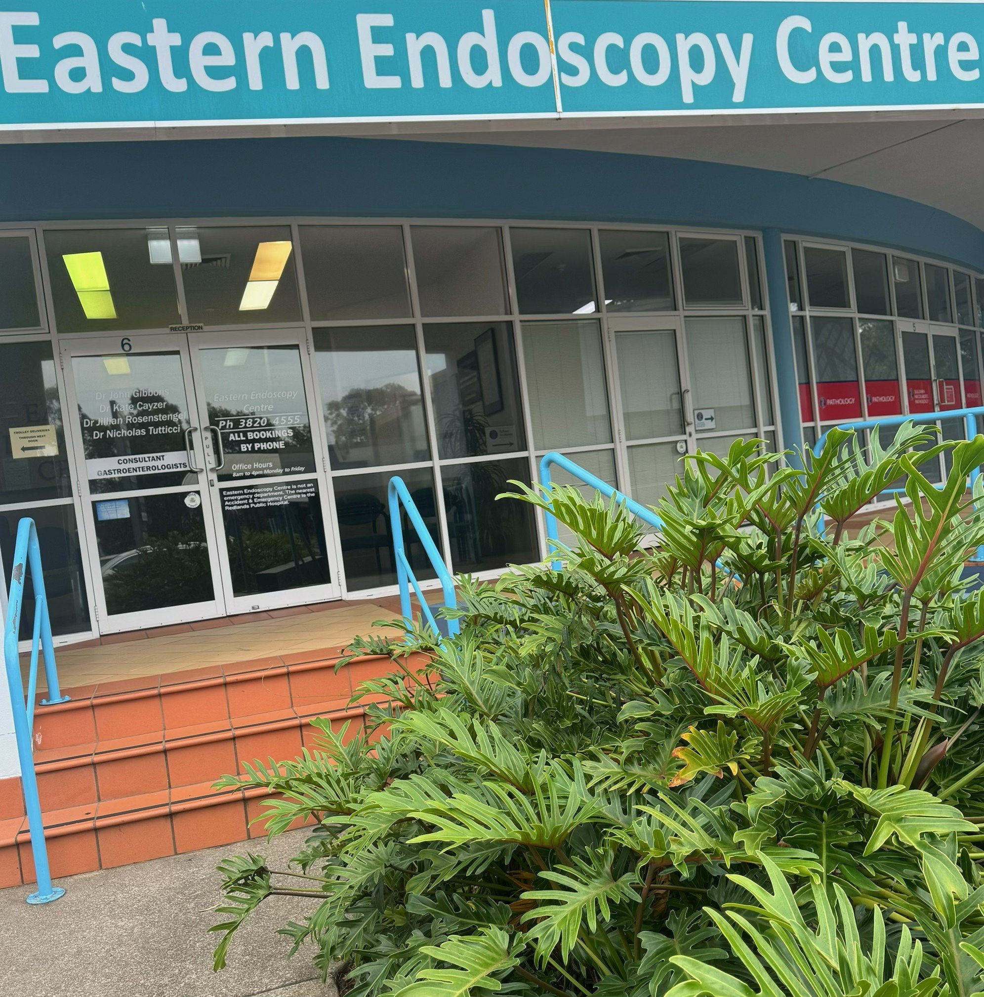 Exterior of the Eastern Endoscopy Centre with glass windows, a sign above the entrance, and lush green plants in the foreground.