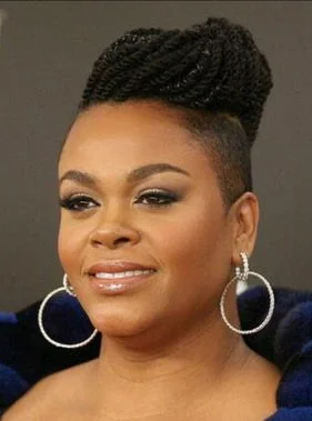 Close-up of an African American woman with styled hair, wearing large hoop earrings, makeup, and a dark top.