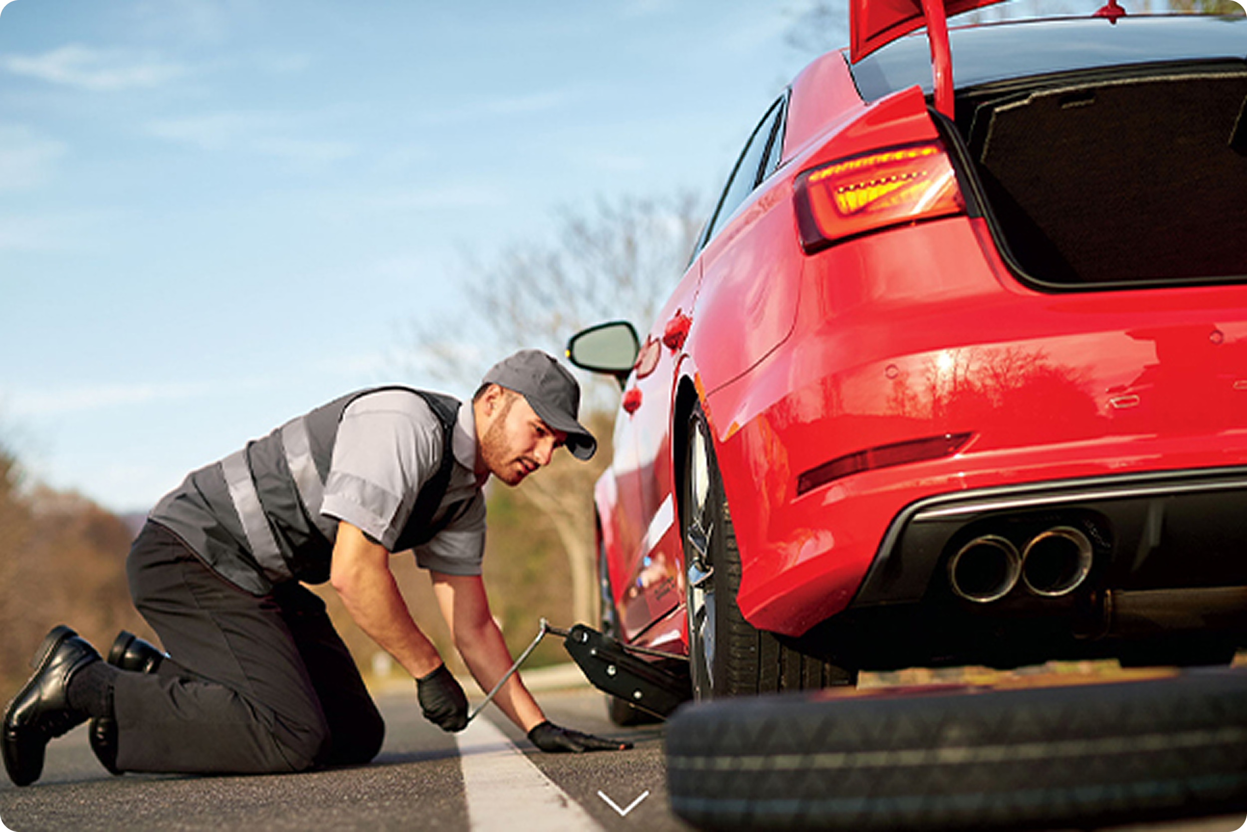 A police officer kneeling on the road, inspecting a red sports car that is stopped on the street during the daytime.