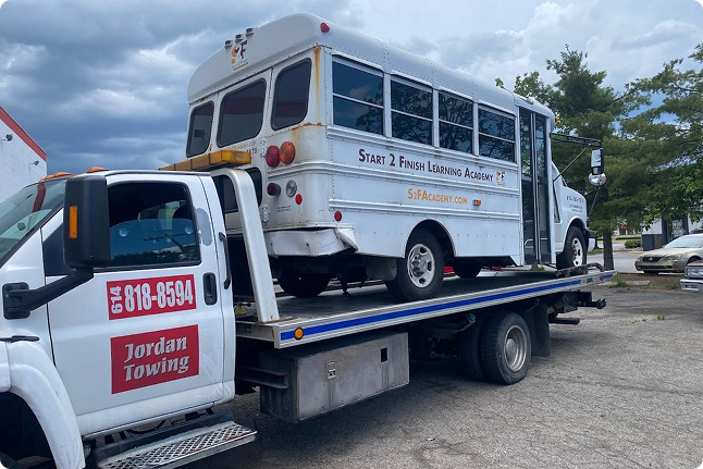 A school bus converted into a mobile learning academy on a flatbed tow truck.
