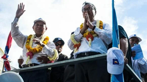 Sam Rainsy, right, and Kem Sokha - the leaders of the Cambodian National Rescue Party (CNRP) greet&nbsp;crowds as they roll through Phnom Penh atop a customized tuk-tuk.