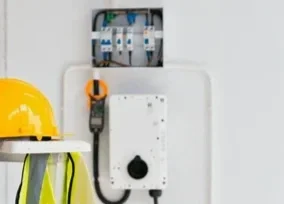 Electrical control panel and a yellow safety helmet on a nearby table.