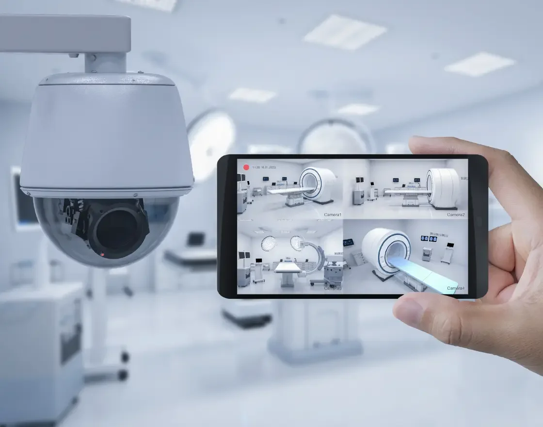 A person is holding a smartphone taking a picture of a medical imaging machine in a hospital radiology room.