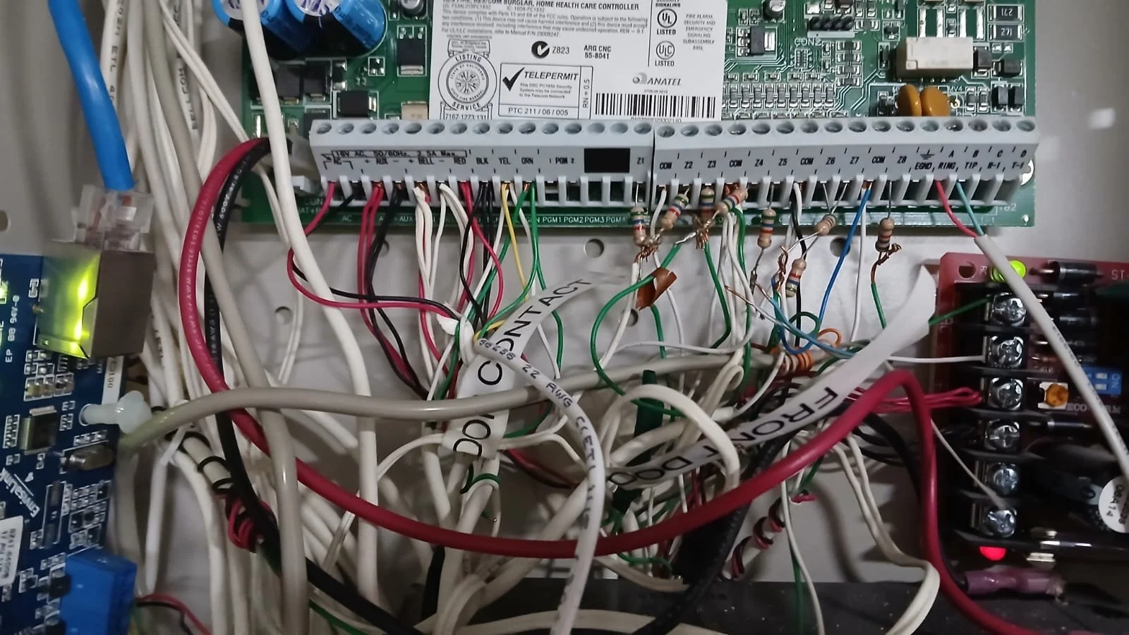 Inside view of an electronic control panel with numerous wired connections, circuit boards, and electronic components.