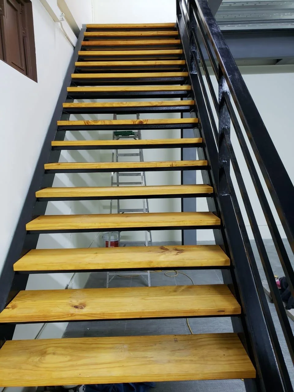 A staircase with wooden steps and black metal frame, leading up to an upper floor.