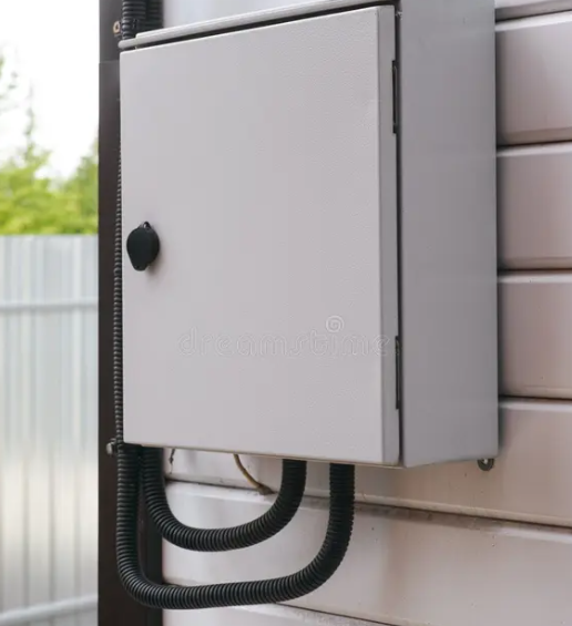 Close-up of an electrical weatherproof junction box mounted on the exterior wall of a building.