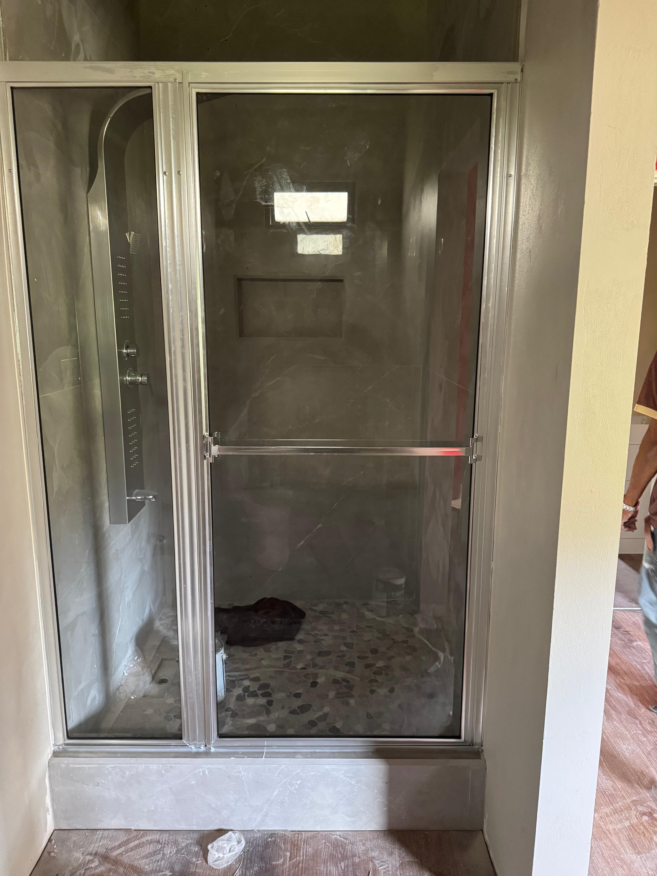 Empty shower with glass door and marble tiles on the floor