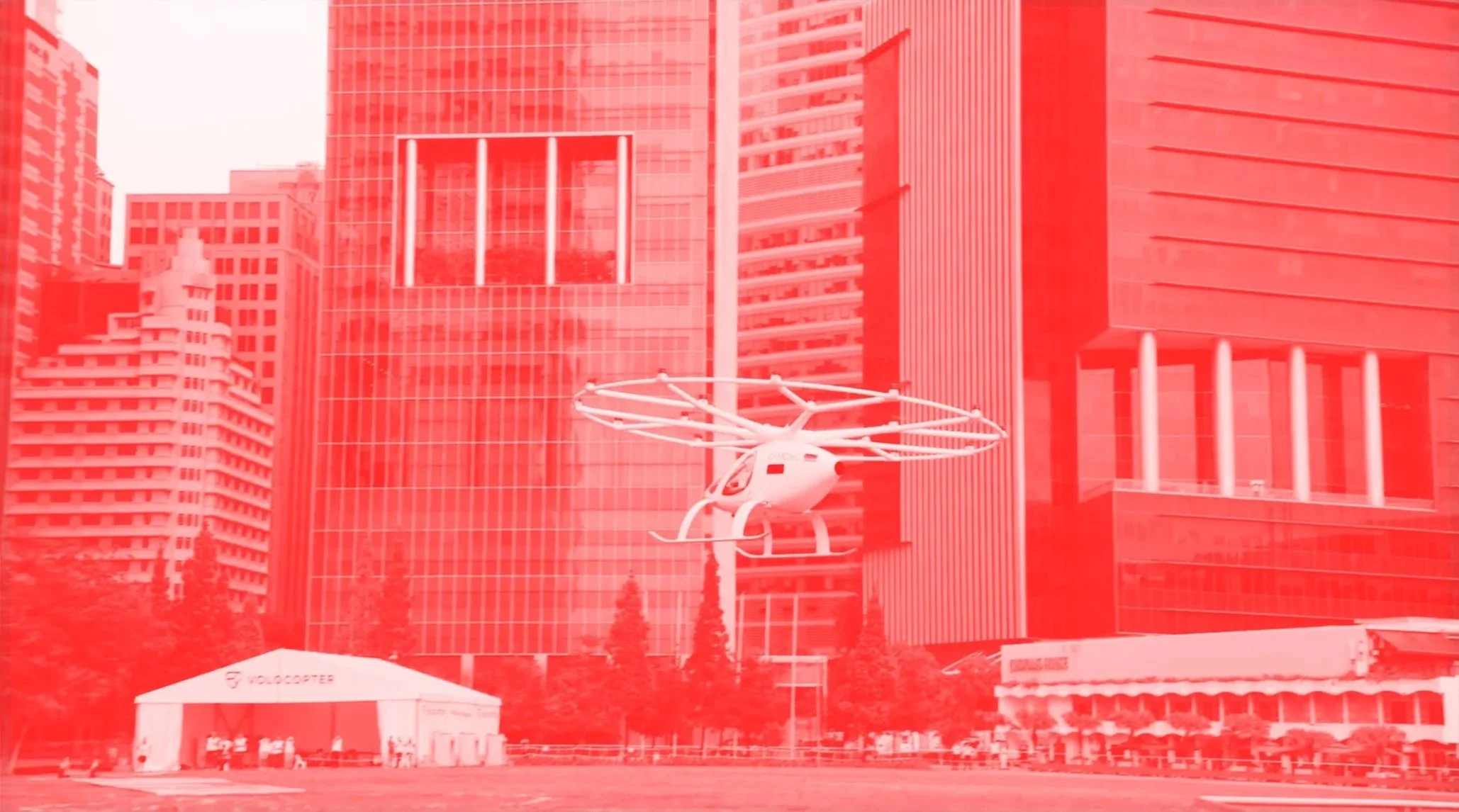 A helicopter flying over Singapore, in front of tall modern buildings with reflective glass facades.