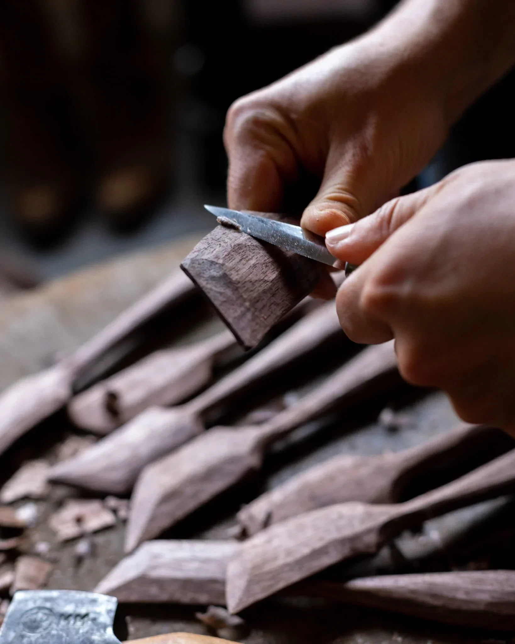 Close-up of a hand carving wood with a small, sharp chisel tool.