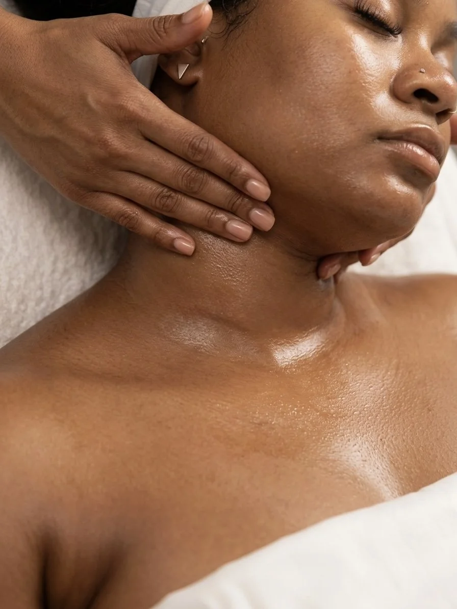 Une personne reçoit un massage du cou et de la nuque, allongée sur une surface rembourrée, avec la peau légèrement brillante et bien hydratée.