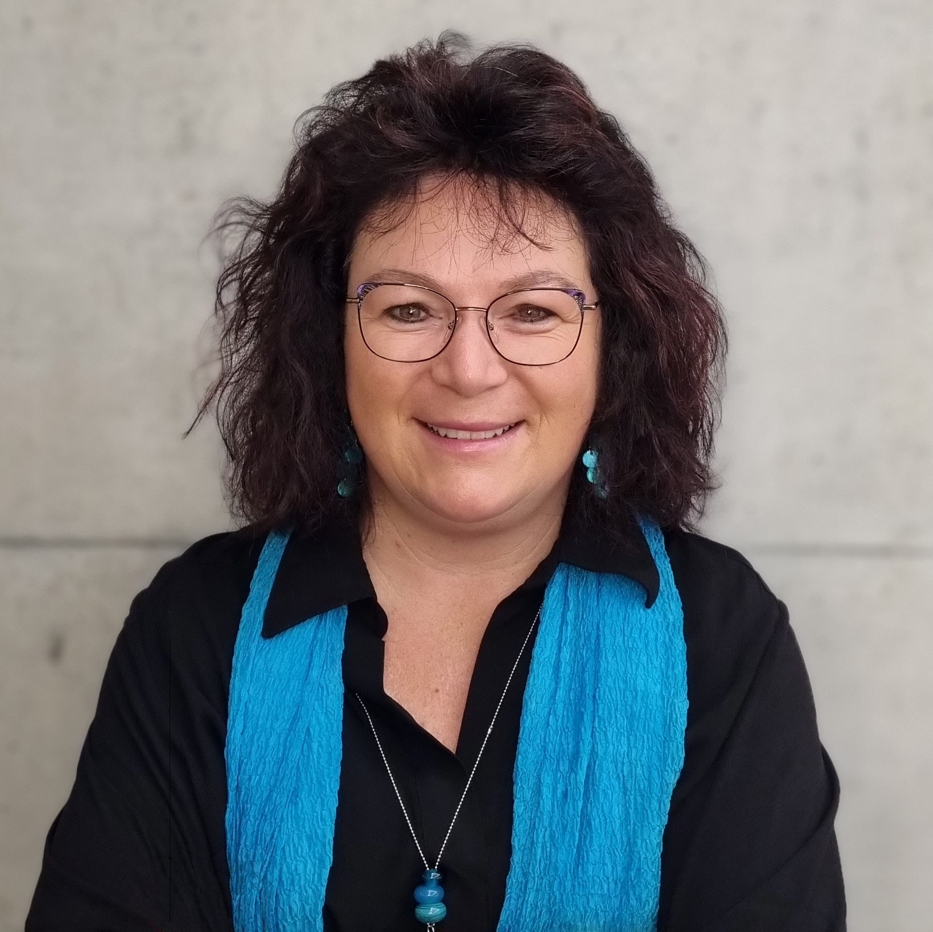 Porträt von Cornelia Salvador, Administration, Kaufmännische Angestellte, vor einer hellen Betonwand.