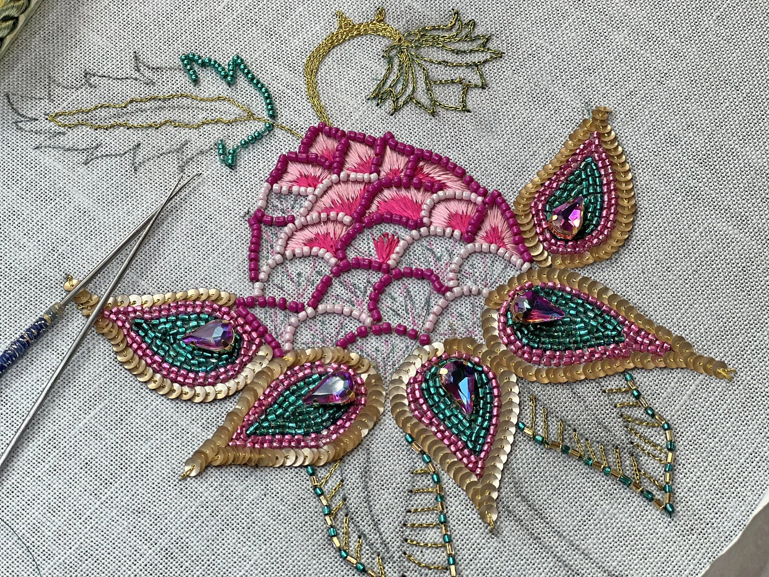 Une broderie en perles colorées représentant des motifs floraux et un papillon.