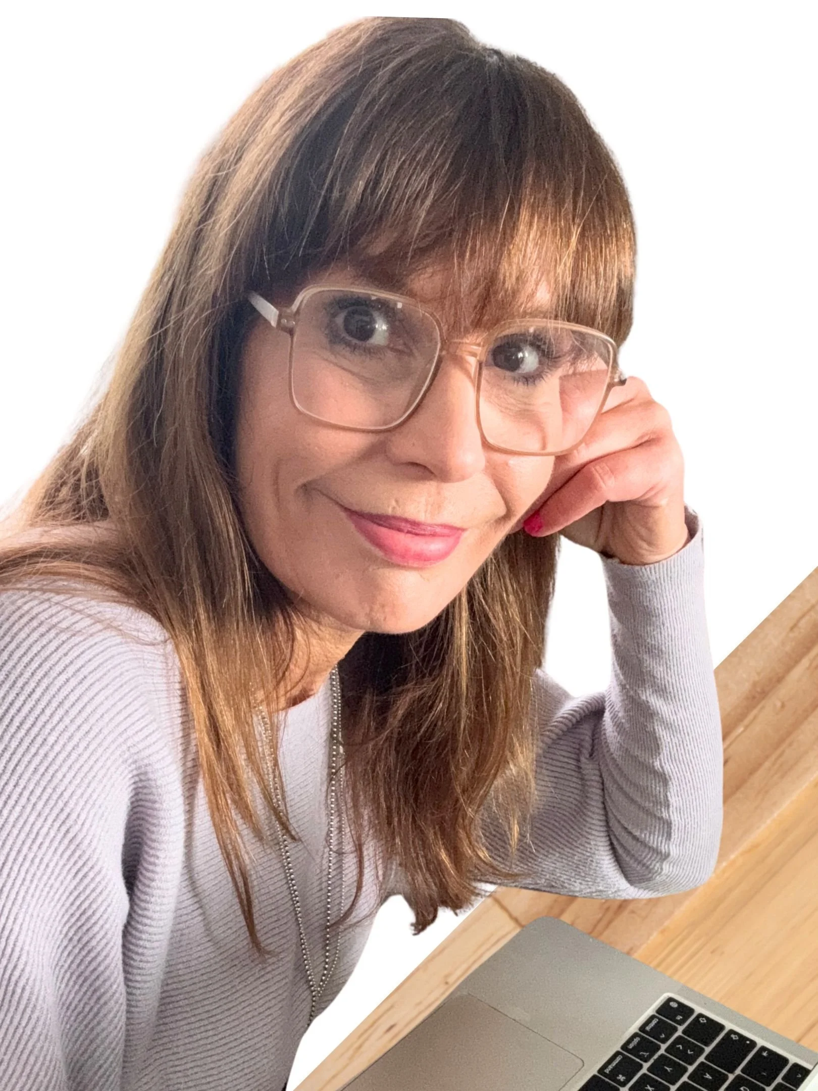 Frau mit Sonnenbrille und weißem Pullover trinkt Kaffee am Holztisch neben einem Laptop