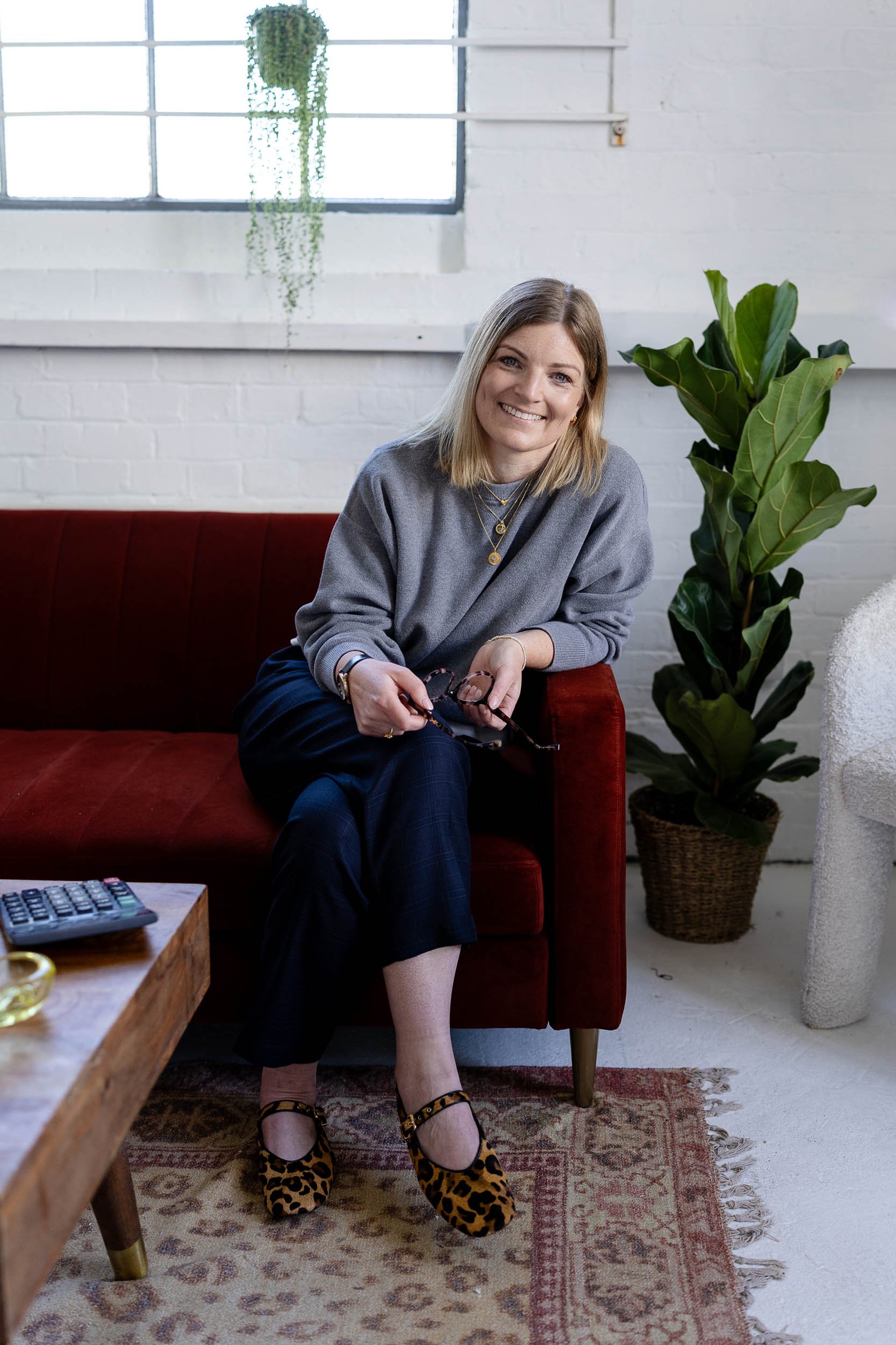 Retail consultant headshot sitting on red sofa