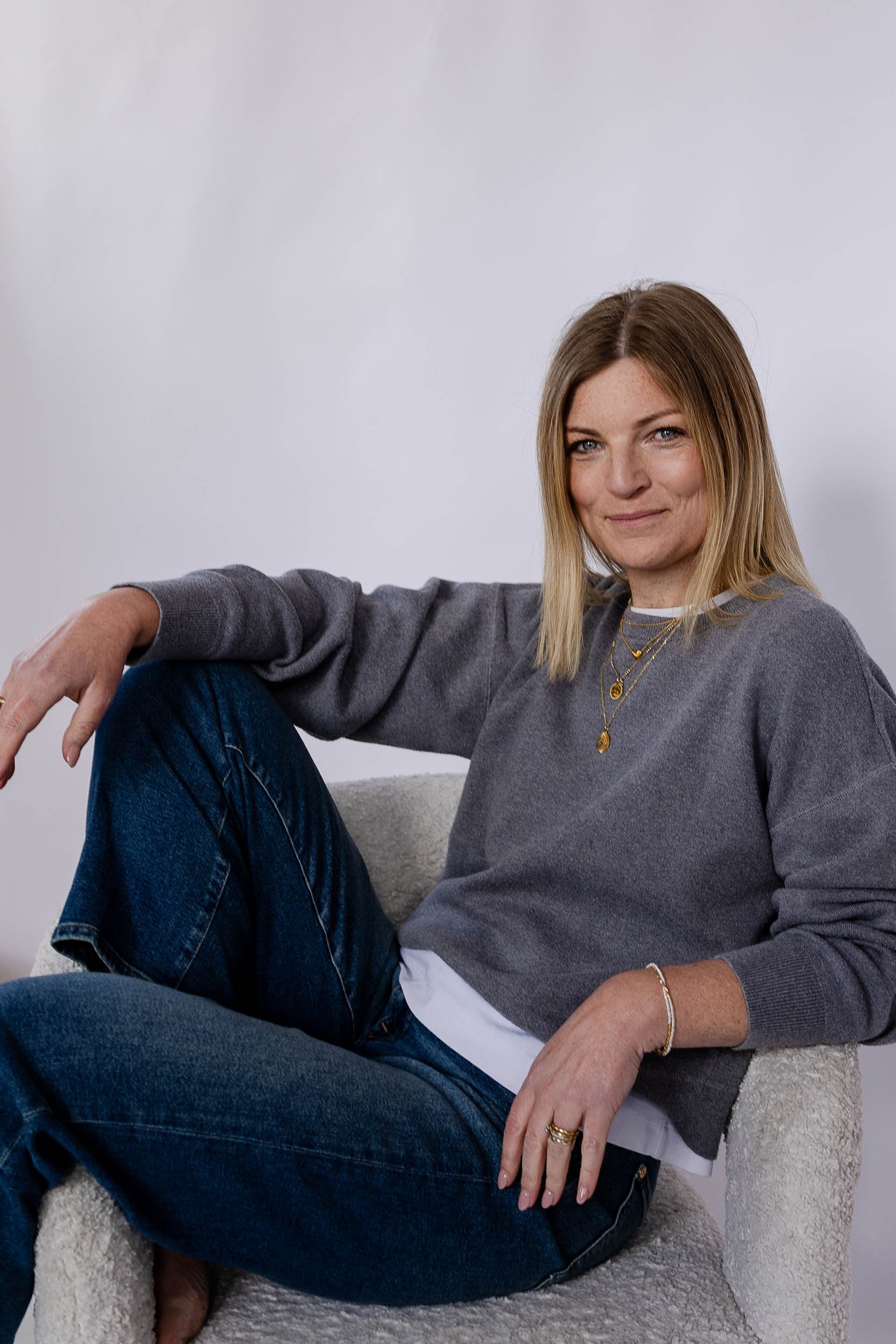 Retail consultant headshot sitting on chair in white studio