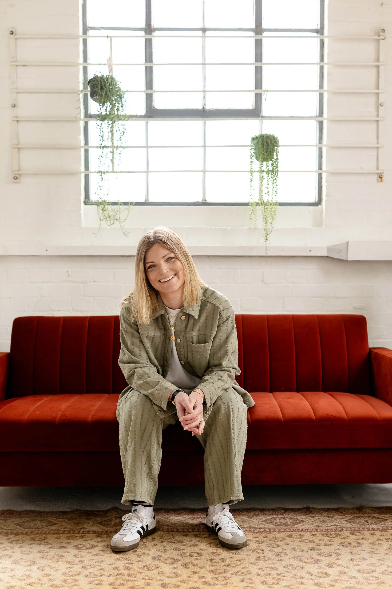 Smiling headshot of fashion merchandising specialist sitting on red sofa