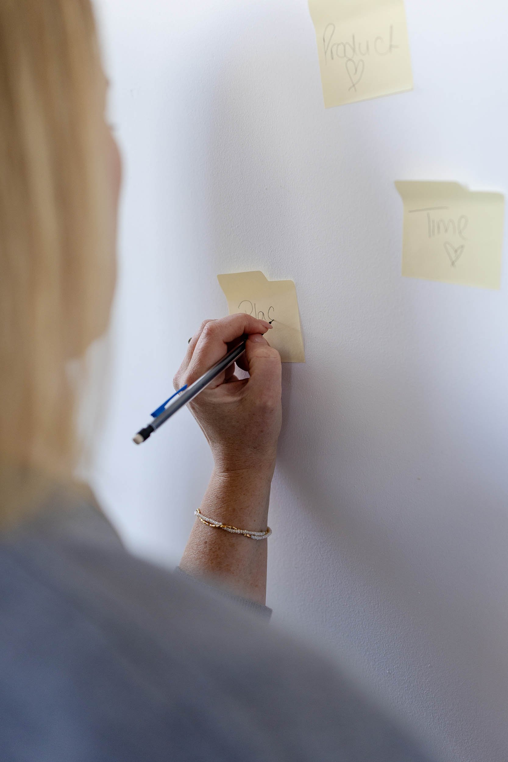 Fashion merchandising consultant writing on yellow post-it notes against wall