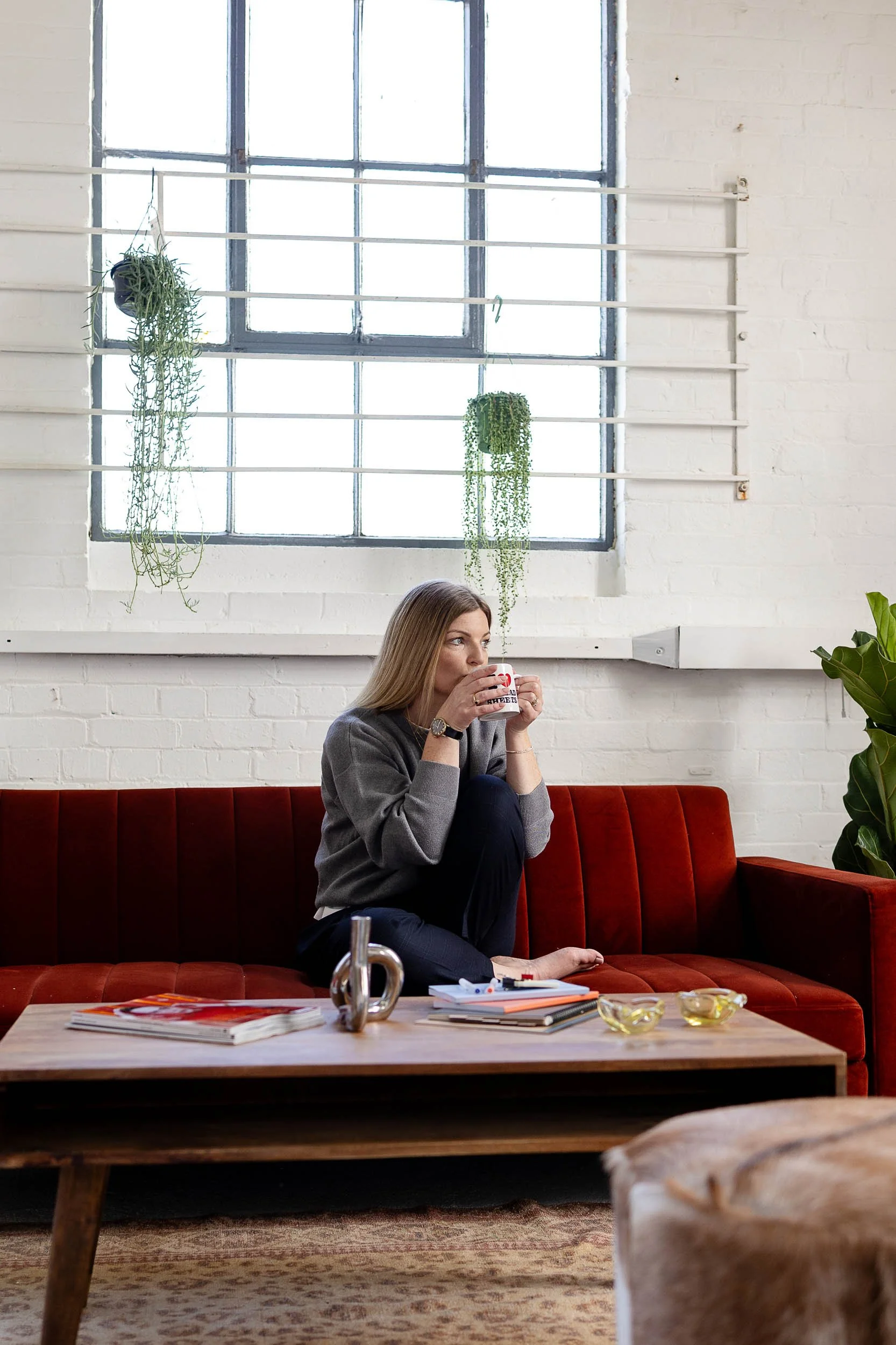 Fashion merchandising consultant drinking tea on red sofa in studio