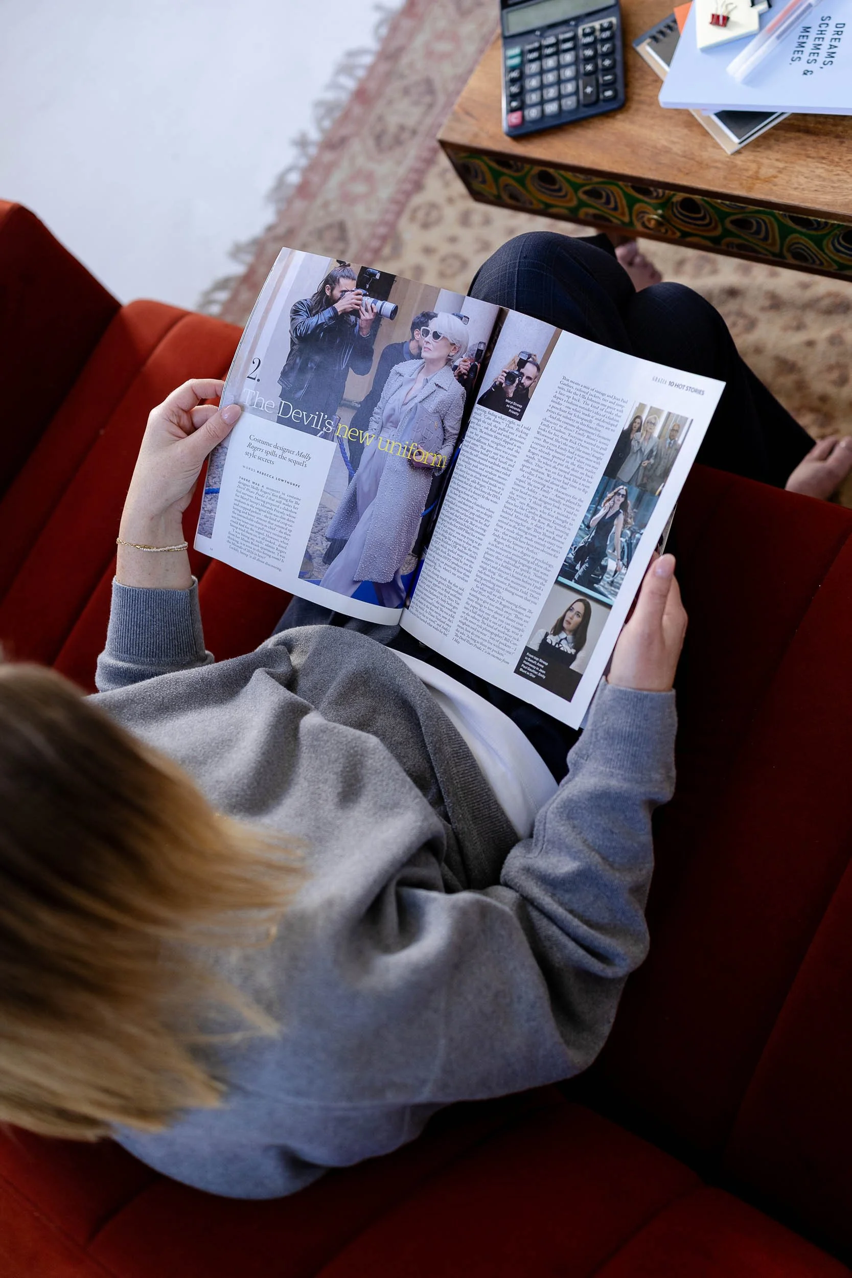 Merchandising consultant sat on red chair reading fashion magazine