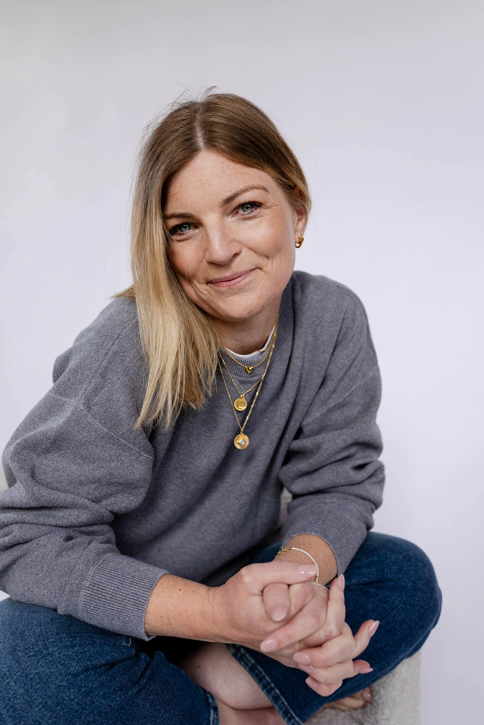 Headshot of retail merchandising consultant wearing grey jumper and smiling