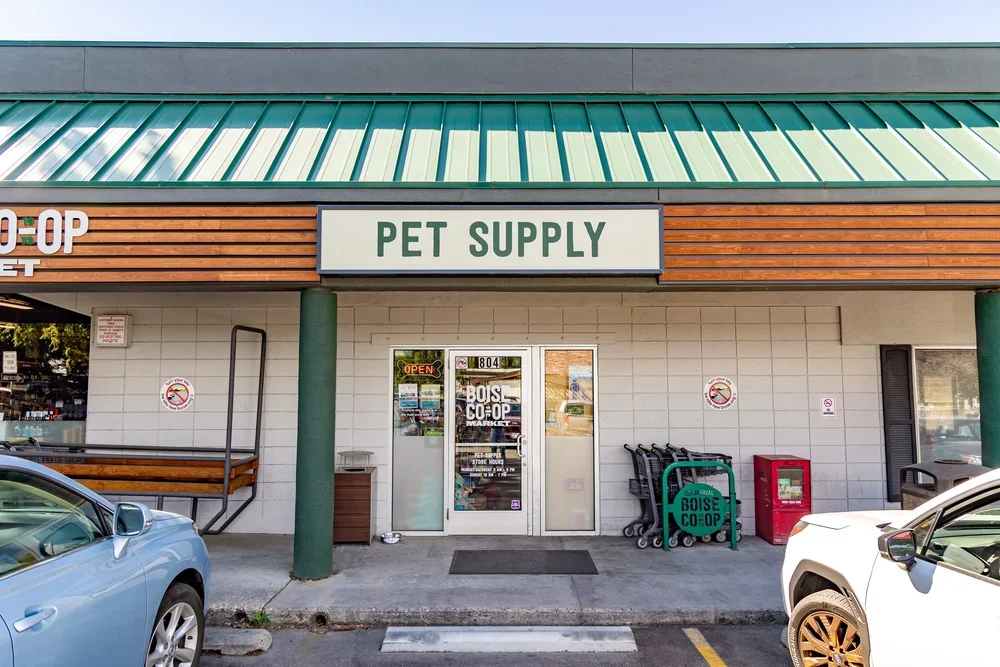 Storefront with a sign reading 'PET SUPPLY' at Boise Co-Op market, located at 804, with shopping carts and a red trash bin outside.