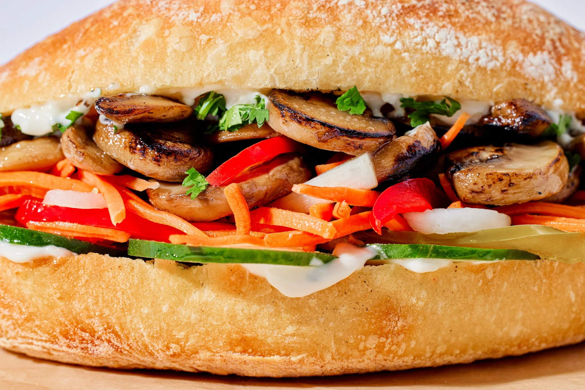 Close-up of a sandwich with grilled chicken, vegetables, and sauce in a crusty bread bun.
