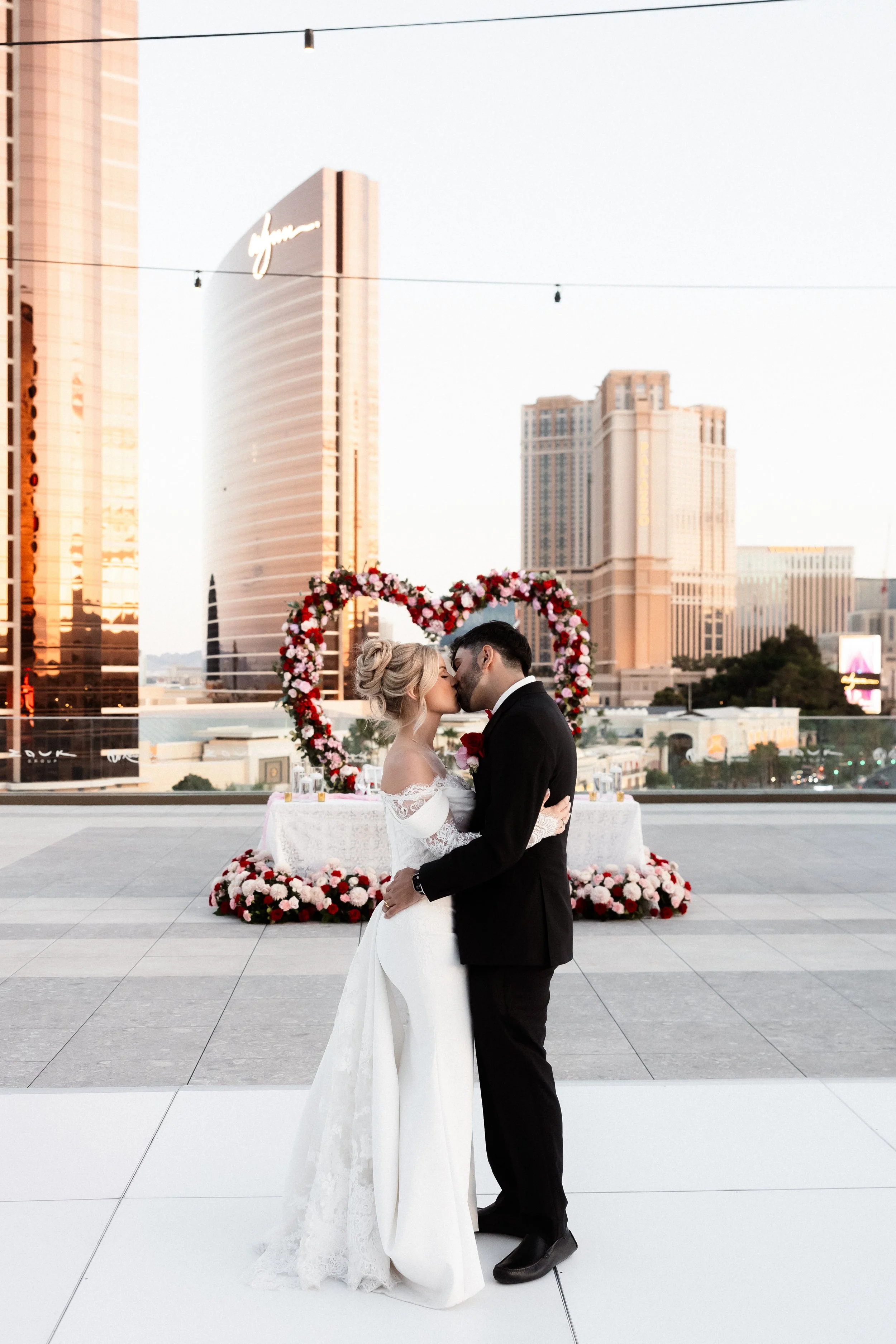 Bride and groom kissing on rooftop with Las Vegas Strip and Wynn in background, bridal hair by Katie A and makeup by Aimee A for Amelia C & Co, photography by Risky Exposure