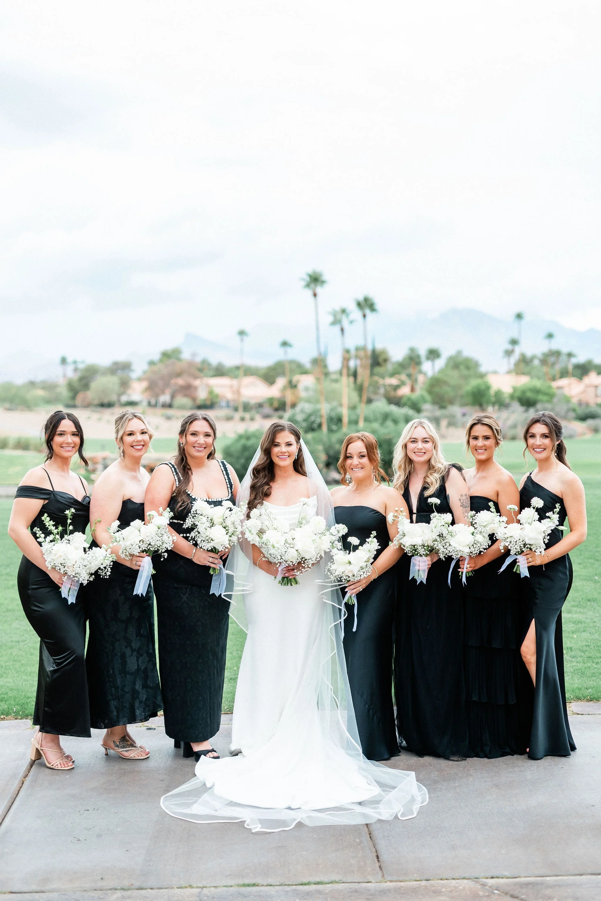 Bride and bridal party in black dresses with white bouquets at Canyon Gate Country Club Las Vegas, hair and makeup by Amelia C & Co, photography by Kristen Marie Weddings